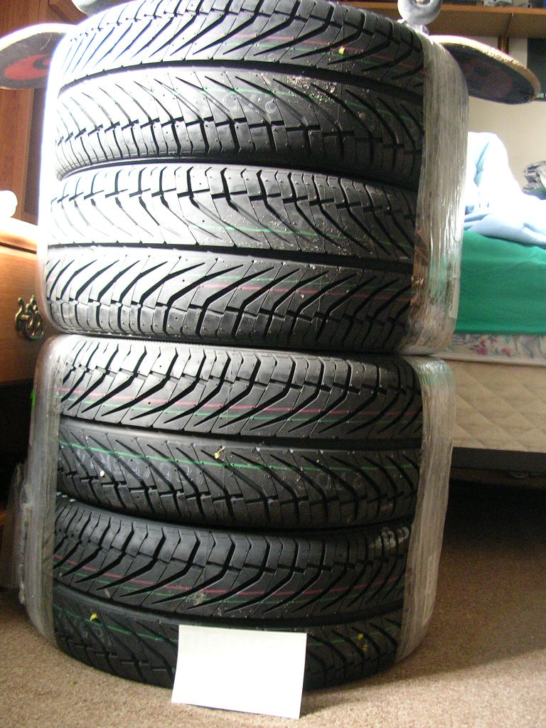 Stack of four tires wrapped in plastic