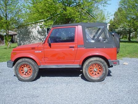 1978 Ford Bronco - Side view of a red Suzuki Samurai with a black soft top and spare tire on the rear.