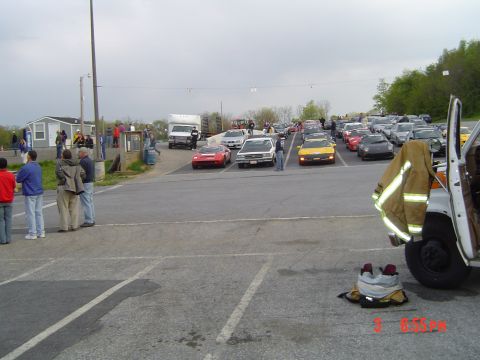 1999 Ford Crown Victoria - A variety of vehicles and spectators are present in an outdoor parking area.