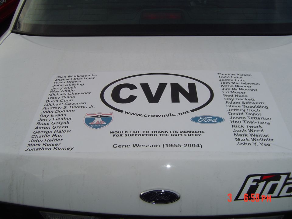 White car trunk with CVN sticker, Ford logo, and Supermotors.net text