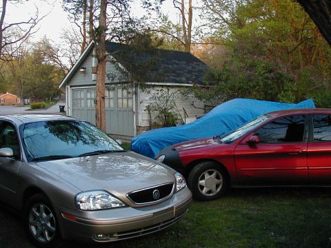 1997 Ford Taurus - Three vehicles are parked in a grassy area in front of a detached garage.