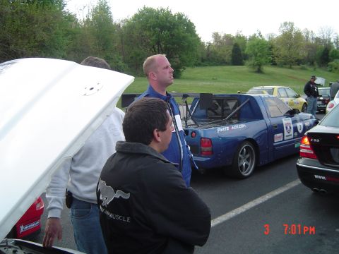 1999 Ford Crown Victoria - A group of people stand around a modified pickup truck with racing decals and a large spoiler.