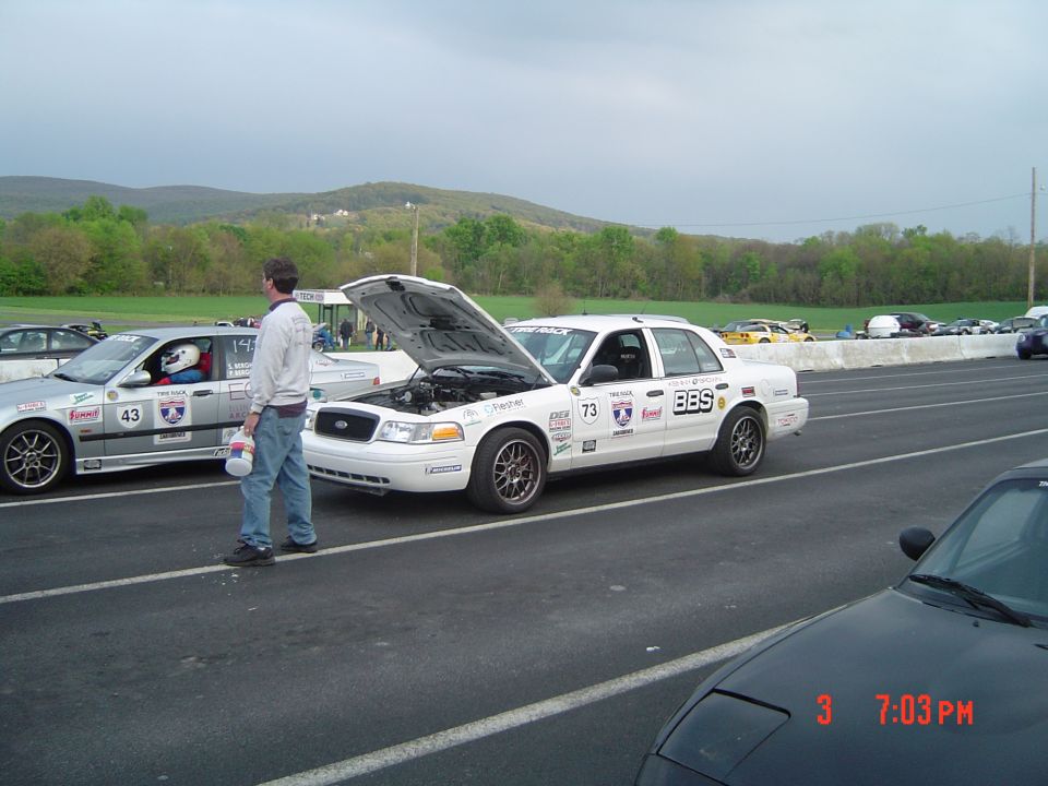 White race car with hood open, number 73 and BBS logos. Another race car with number 43 is to the left