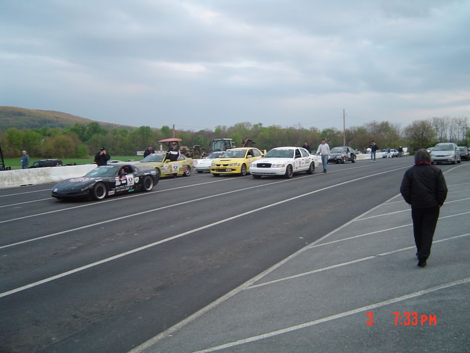 White police car with racing decals on a track, 3q-front view
