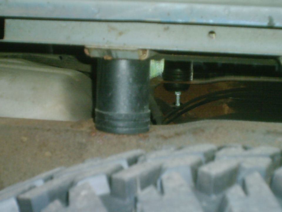 Under-vehicle close-up of a rubber bump stop and ball joint above an off-road tire