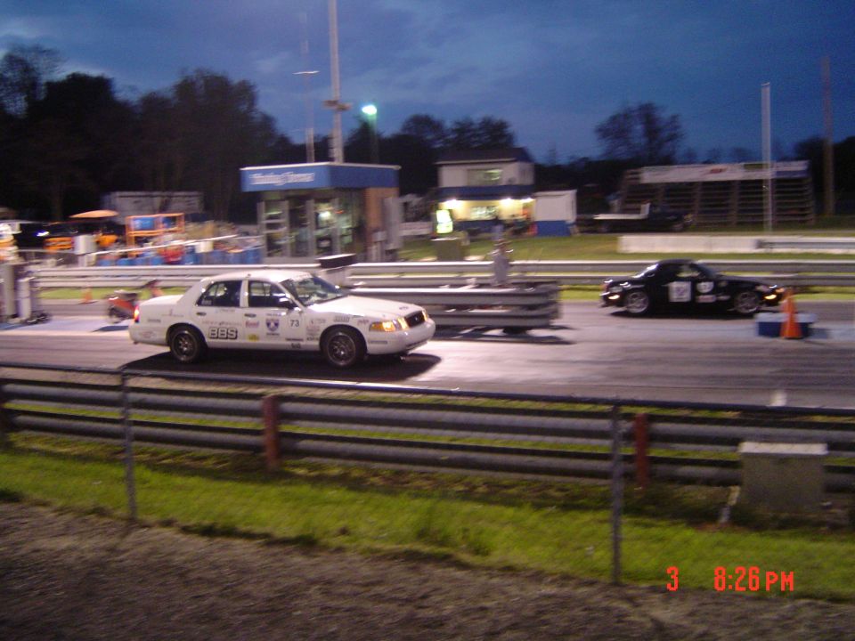 White 1999 Ford Crown Victoria race car with racing decals, seen from the front-right