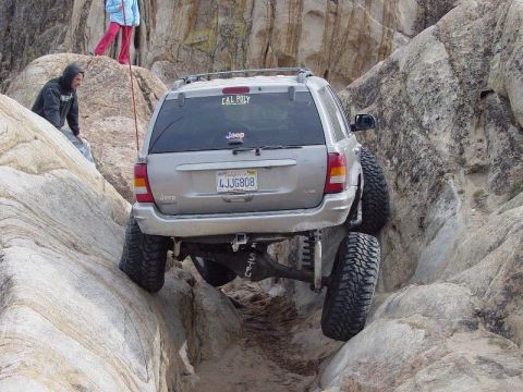 1999 Jeep Grand Cherokee - This modified Jeep Grand Cherokee is tackling a challenging off-road course with one wheel off the ground.