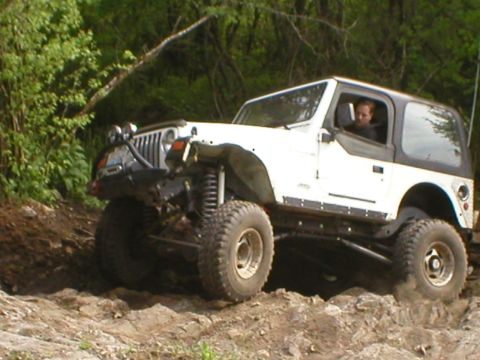 1978 Ford Bronco - White Jeep Wrangler navigating a challenging rocky terrain during an off-road excursion.