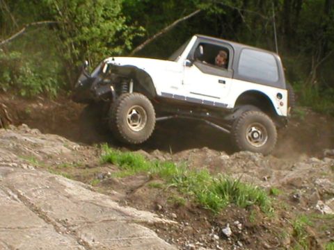 1978 Ford Bronco - A white Jeep Wrangler navigates a challenging rocky terrain on an incline.