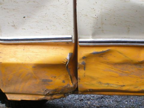 1978 Ford Bronco - Close-up view of a damaged door seam on a yellow and white vehicle, showing rust and significant dents.