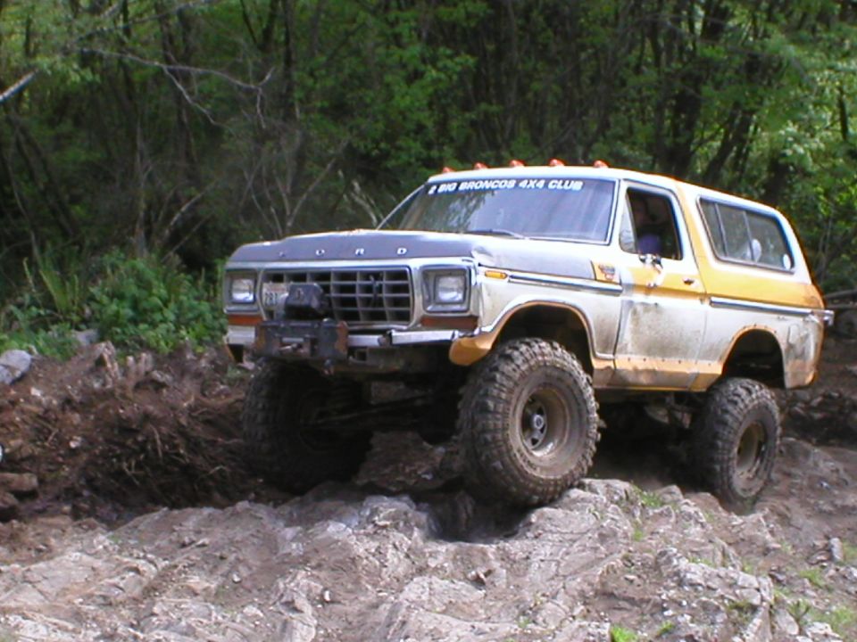 White and yellow 1978 Ford Bronco with large tires on rocky terrain