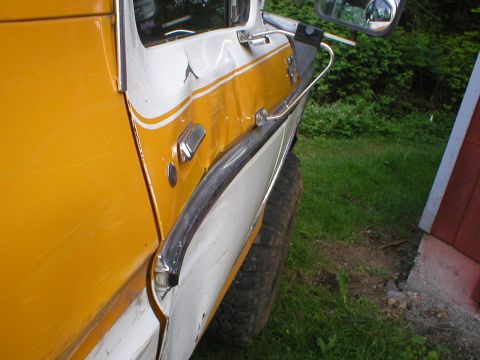 1978 Ford Bronco - The side panel of a two-tone 1978 Ford Bronco shows damage near the door handle and trim.
