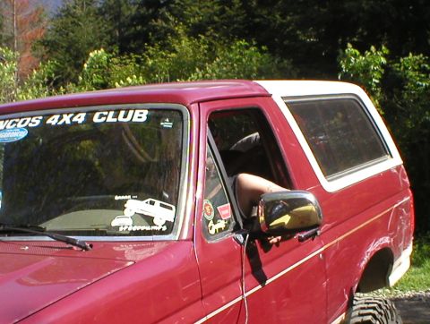 1978 Ford Bronco - A red Ford Bronco with a white removable top is parked outdoors with trees in the background.
