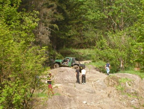 1978 Ford Bronco - Two off-road vehicles are seen on a challenging rocky path with several people observing the action.