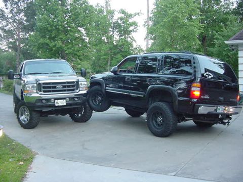 2000 Chevrolet Tahoe - A lifted Ford F-250 truck is positioned on top of a black Chevrolet Tahoe SUV.
