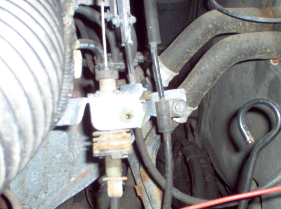 Close-up of engine bay hoses and cables with a white plastic component