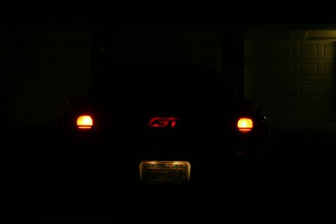 1995 Ford Probe - The rear of a car is visible at night, with its taillights illuminated and a GT emblem on the trunk.