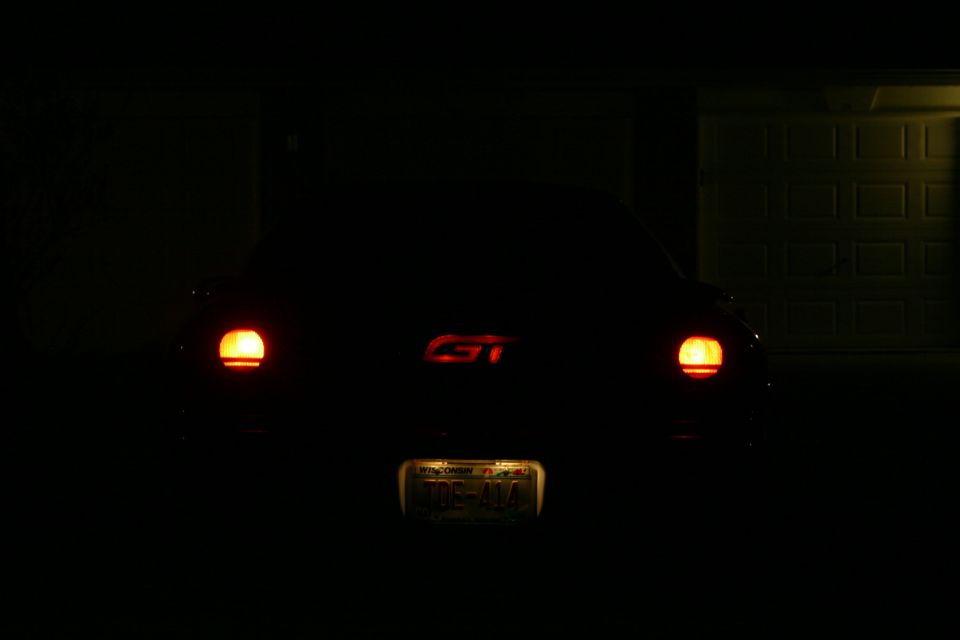 car's rear with taillights on and a GT badge