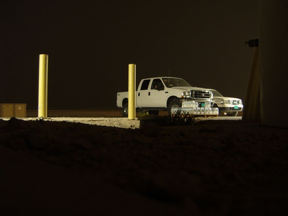 White pickup truck parked at night next to another vehicle