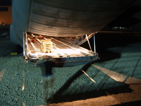1988 Ford Bronco - A cargo ramp is lowered at night, with a person blurred by motion loading crates.
