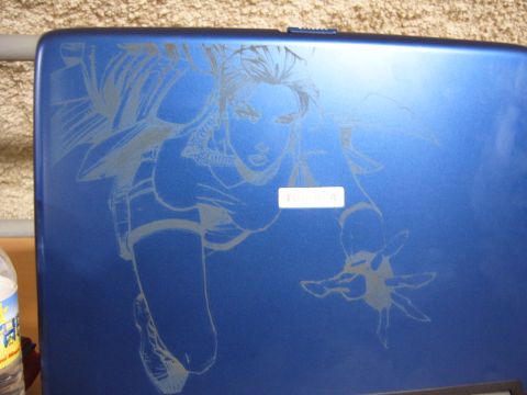 1988 Ford Bronco - A blue laptop features an etched comic book character design, with a small white label visible on its surface.