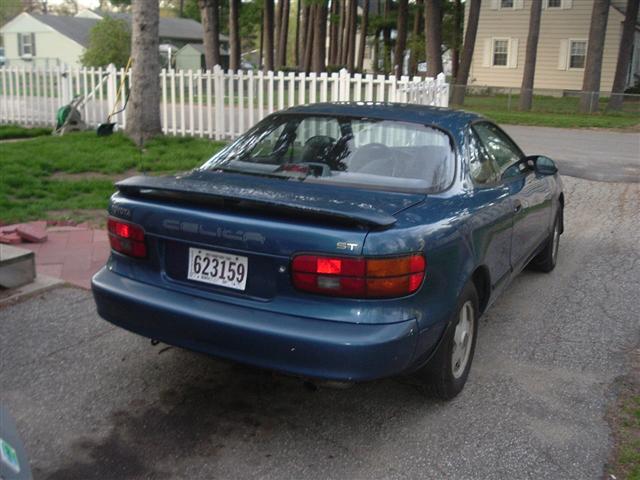 Teal Toyota Celica ST coupe rear three-quarter view parked by a picket fence