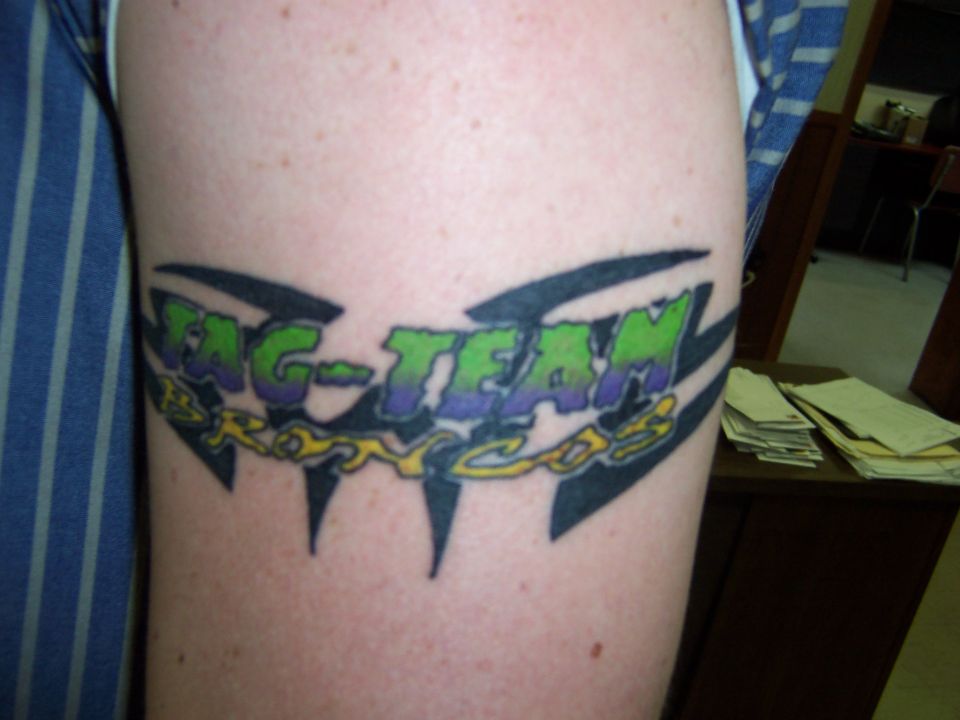 Arm tattoo with tribal points and green-purple text reading Tag-Team Broncos