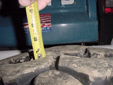 1971 Ford Bronco - A tape measure is used to check the tread depth on a tire, with a portion of the vehicle body visible in the background.