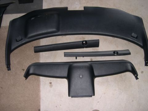 1997 Ford Probe - Several black plastic interior trim components are displayed on a concrete surface.