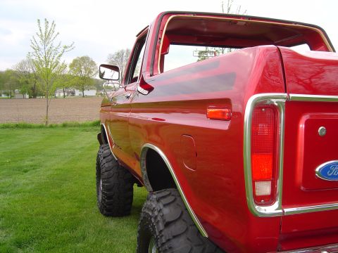 1978 Ford Bronco - Rear view of a red 1978 Ford Bronco parked on grass with a field in the background.