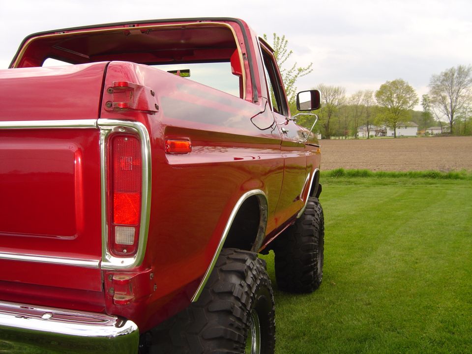 red pickup truck, lifted with big tires, parked on grass