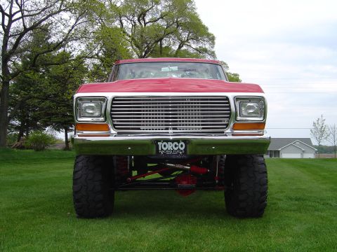 1978 Ford Bronco - A lifted 1978 Ford Bronco is shown from the front on a grassy lawn with trees in the background.