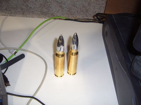 1988 Ford Bronco - Two large bullet casings with chrome tips are displayed on a table with various cables and electronics.
