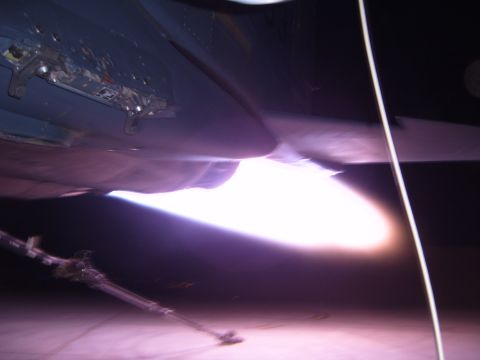 1988 Ford Bronco - The bright exhaust of a jet engine is visible, with a metal rod and cable nearby.
