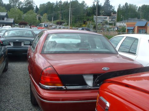 1999 Ford Crown Victoria - Rear view of a red Ford Crown Victoria parked in a lot with other vehicles.