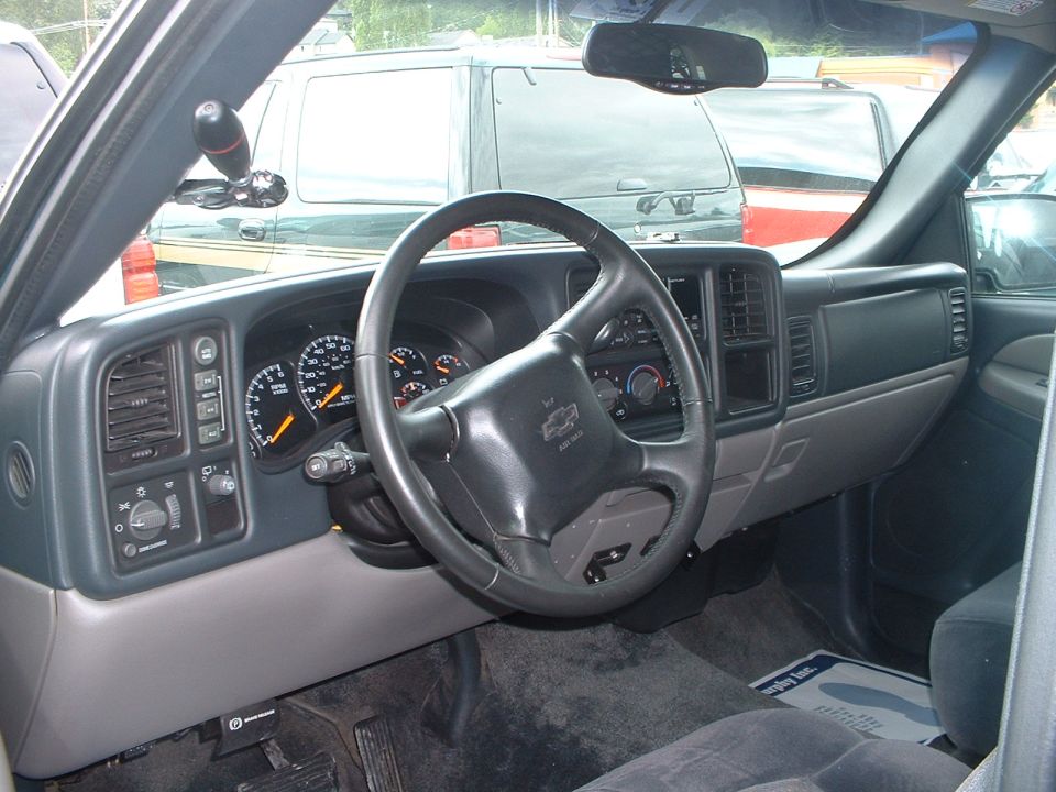 Dashboard and steering wheel of a Chevrolet Silverado or GMC Sierra truck, with other vehicles visible through the windshield