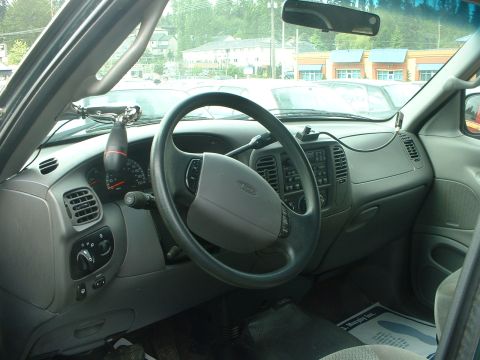 1999 Ford Crown Victoria - The interior of a pickup truck is shown, a gray dashboard, steering wheel, and various controls.