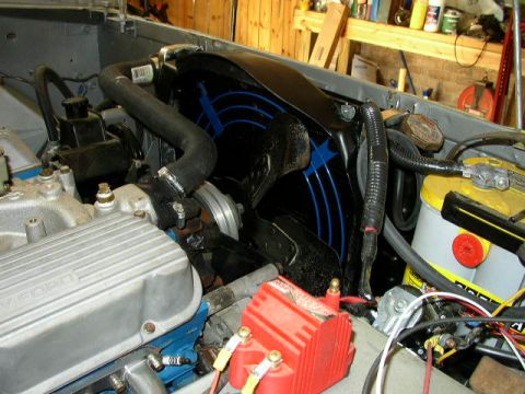 1995 Ford Bronco - Close-up view of a vehicle's engine bay, highlighting the fan shroud, battery, and a Ford-branded valve cover.