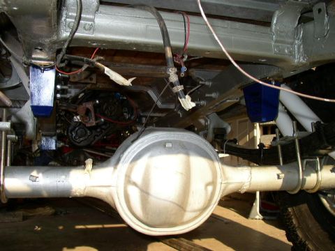 1995 Ford Bronco - Underside view of a vehicle's rear axle and suspension system, leaf springs and blue shock absorbers.