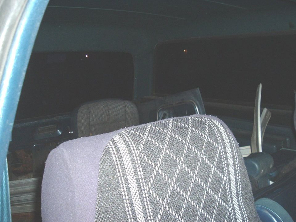 Back seats of a vehicle, looks like a truck or SUV. Dark interior with patterned seat covers