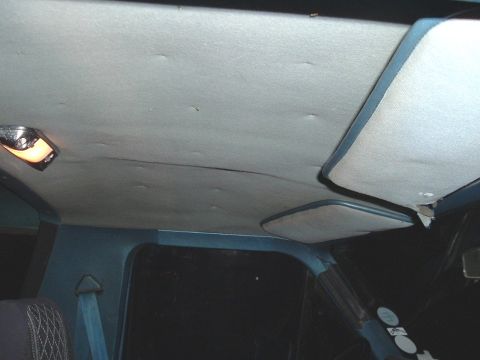 1982 Ford Bronco - The interior ceiling of a vehicle shows a dome light and two sun visors.