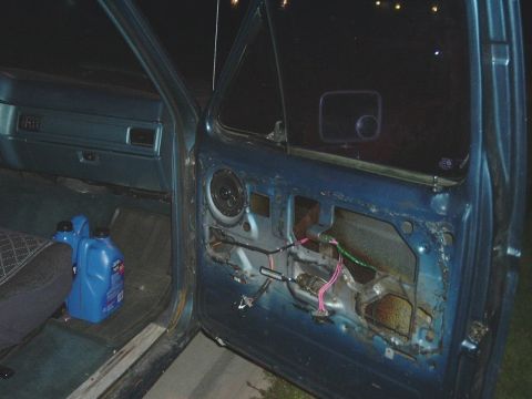 1982 Ford Bronco - Car door interior with speaker and wiring visible, plus two oil containers on the floor.