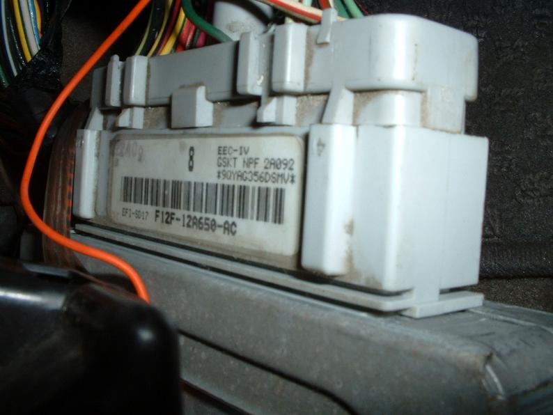 Close-up of EEC-IV engine computer module with orange wire and white connector