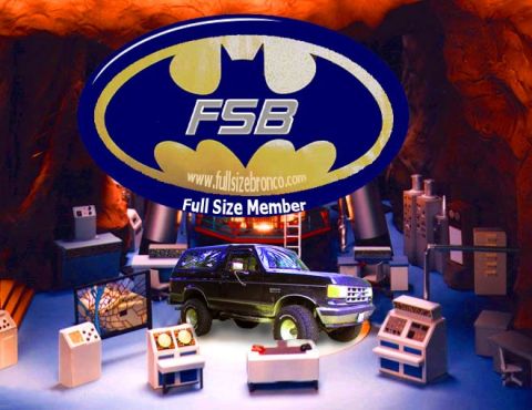 1988 Ford Bronco - A dark Ford Bronco is positioned in a Batcave-like environment, surrounded by electronic equipment.