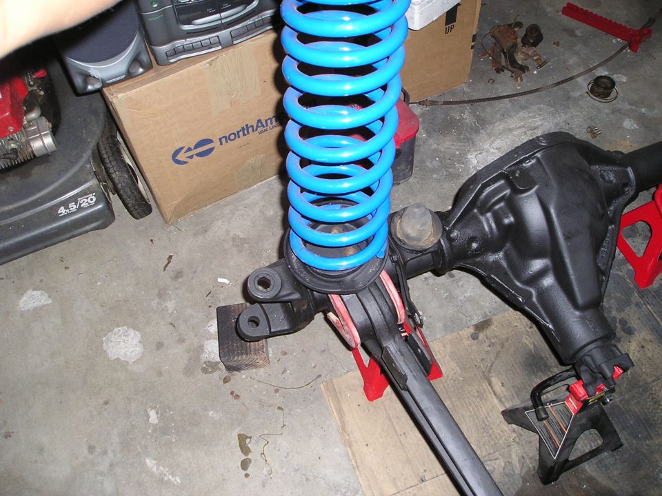 front axle assembly with a bright blue coil spring on jack stands