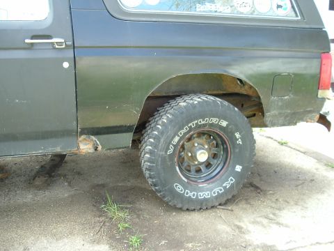 1989 Ford Bronco - This Ford Bronco shows rust damage on its lower body panels and rear wheel arch, indicating wear and tear.