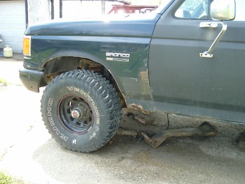 1989 Ford Bronco - This dark green Ford Bronco shows significant rust on its lower body panels and fender.