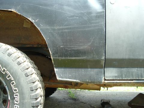 1989 Ford Bronco - Close-up view of the side panel and fender of a black vehicle, showing signs of wear and tear.
