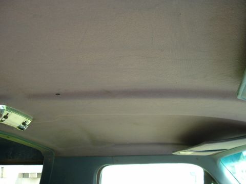 1989 Ford Bronco - The interior headliner of a vehicle is visible, with a dome light fixture and a sun visor.