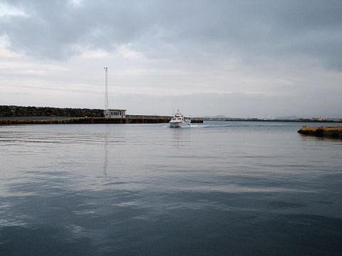 1996 Ford Bronco - A small boat travels across the water near a pier structure under a cloudy sky.